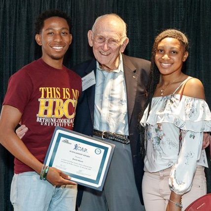 G. Holmes Braddock smiles with two scholarship recipients.